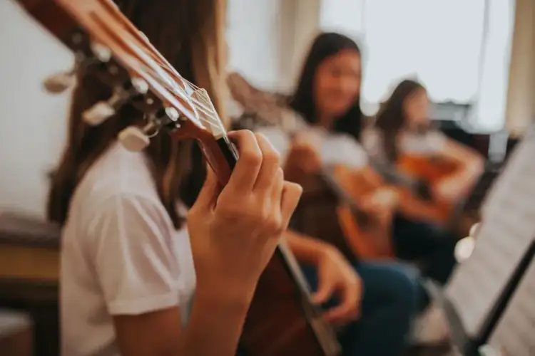 Dziewczyny ćwiczą grę na gitarach, ucząc się, do której klasy jest muzyka.