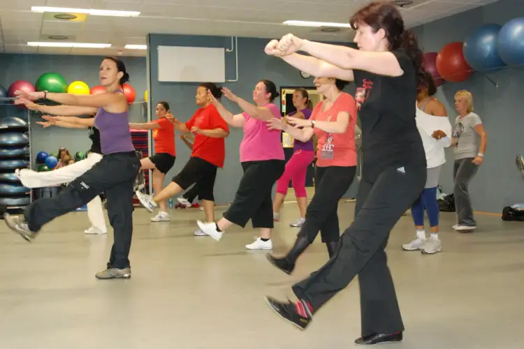 Grupa kobiet ćwiczy w rytm muzyki, wykonując energiczne ruchy. To właśnie zumba – świetna zabawa i trening w jednym!