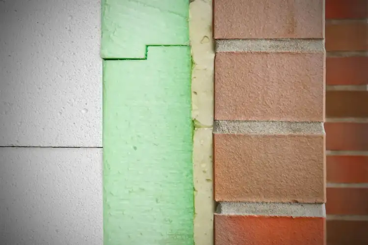 Warstwa białego styroduru, zielona pianka i ceglana fasada. Czy po styrodurze można chodzić? To pytanie o wytrzymałość izolacji.