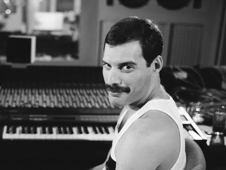 Freddie Mercury z wąsami i w białej koszulce, siedzi przy pianinie. Czy Freddie Mercury miał dzieci? Nie, nie miał.