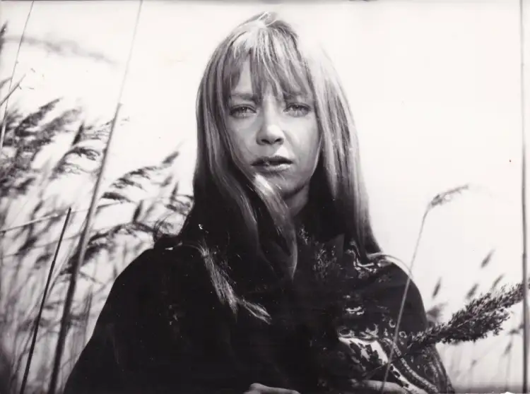 Irena Szczurowska w otoczeniu trzcin, zamyślona, z kosmykami włosów opadającymi na twarz.