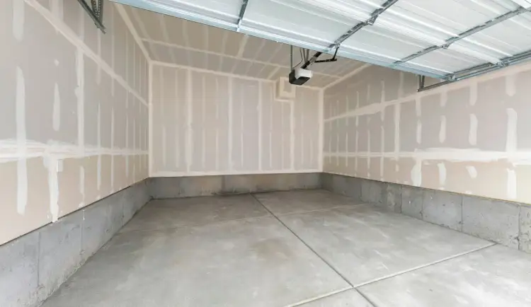 Puste wnętrze garażu z betonową podłogą i nieotynkowanymi ścianami. Idealne miejsce do zastanowienia się, czym ogrzać garaż blaszany.
