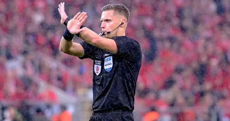 Sędzia w deszczu sygnalizuje decyzję. Ciekawe, ile zarabiają sędziowie w Lidze Mistrzów za takie emocje.