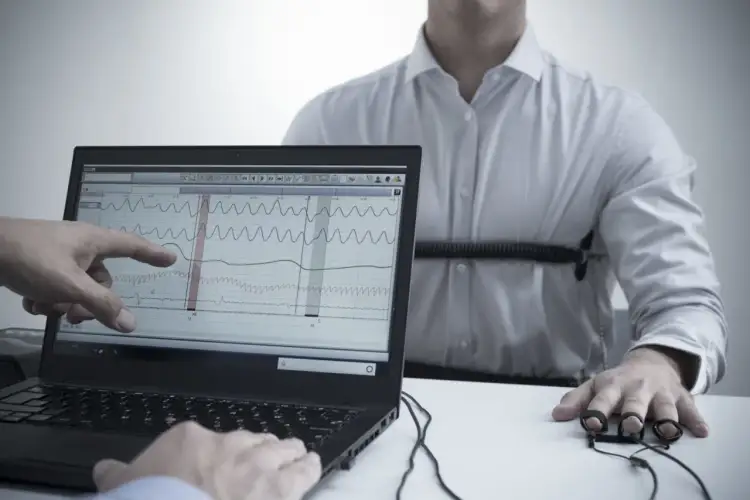 Badanie wykrywaczem kłamstw w Warszawie. Na ekranie laptopa wykresy fizjologiczne, a na ręce mężczyzny czujniki.