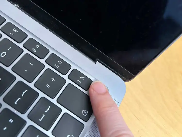 Palec naciska klawisz F12 na klawiaturze MacBook'a.