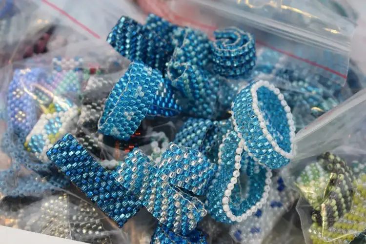 Zbliżenie na ręcznie robione pierścionki i bransoletki z niebieskich koralików w plastikowych woreczkach.