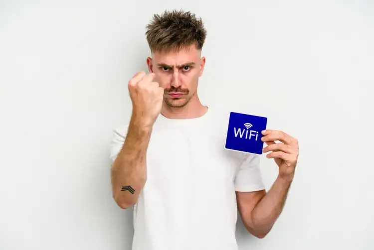 Zirytowany mężczyzna pokazuje kartkę z napisem "WiFi", jakby chciał powiedzieć: "Mam dość! Czas dowiedzieć się, jak zmienić hasło do wifi!".
