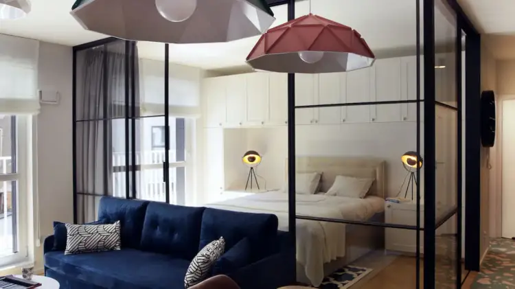 Szklana ściana z czarnymi ramami to stylowy sposób, jak oddzielić sypialnie od salonu, tworząc otwartą przestrzeń.