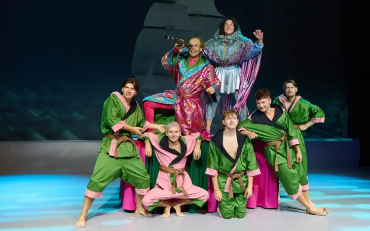 Aktorzy w barwnych strojach na scenie, przygotowujący się do spektaklu "Akademia Pana Kleksa teatr".