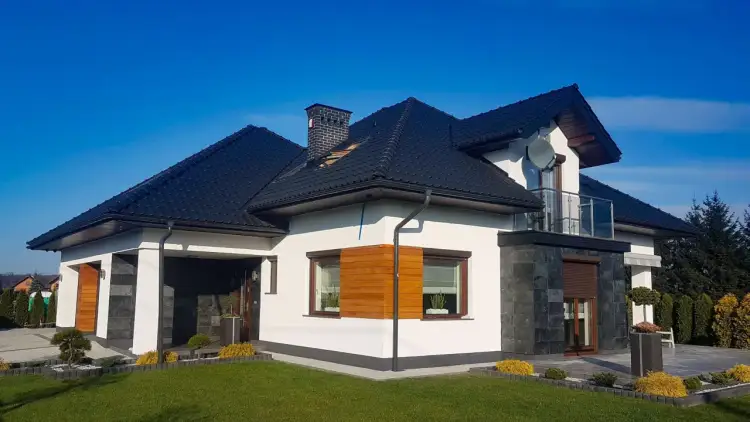 Nowoczesny dom z grafitowym dachem i oknami w kolorze złoty dąb. Elewacja biała z kamiennymi akcentami.