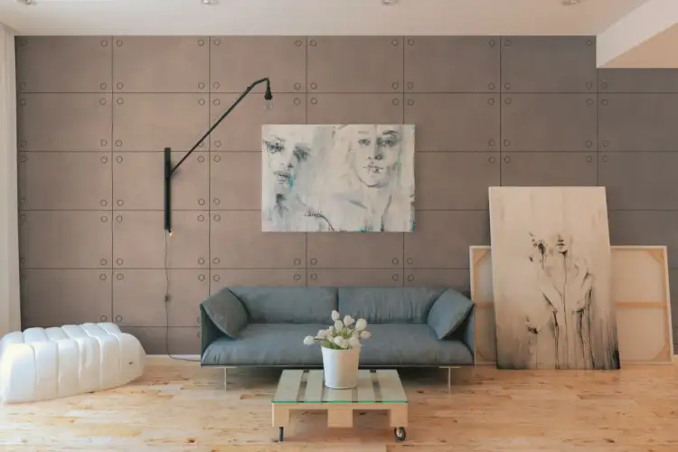Nowoczesne panele ścienne to świetne rozwiązanie co zamiast tynkowania ścian. W salonie szara kanapa, biały puf i obrazy.