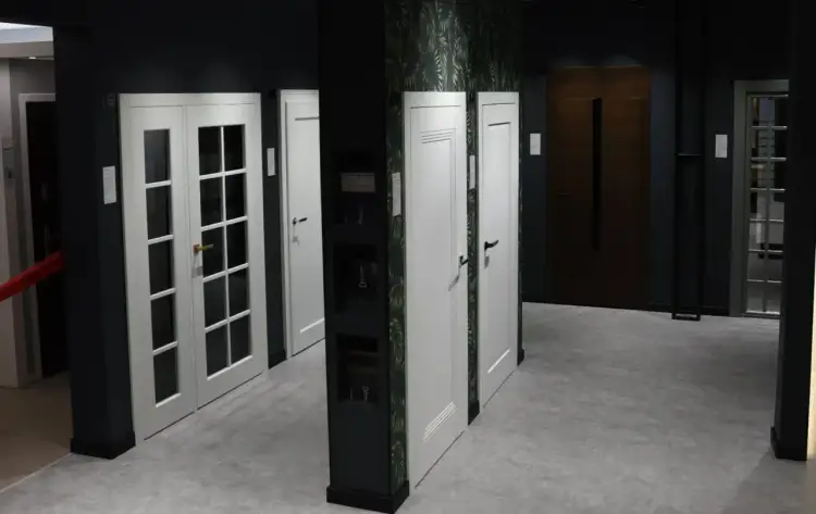 Salon drzwi w Łodzi: białe drzwi dwuskrzydłowe z przeszkleniem, białe drzwi jednolite, brązowe drzwi wejściowe.