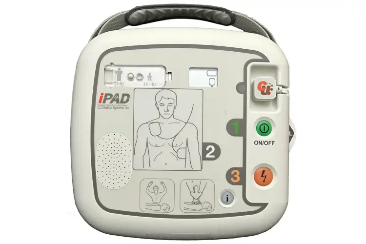 Automatyczny defibrylator zewnętrzny (AED) iPAD w kolorze białym, z widocznymi przyciskami i instrukcjami.