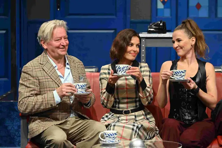 Trójka aktorów w scenografii komedii odlotowej, czyli lumbago, popija herbatę z filiżanek w niebieskie wzory.