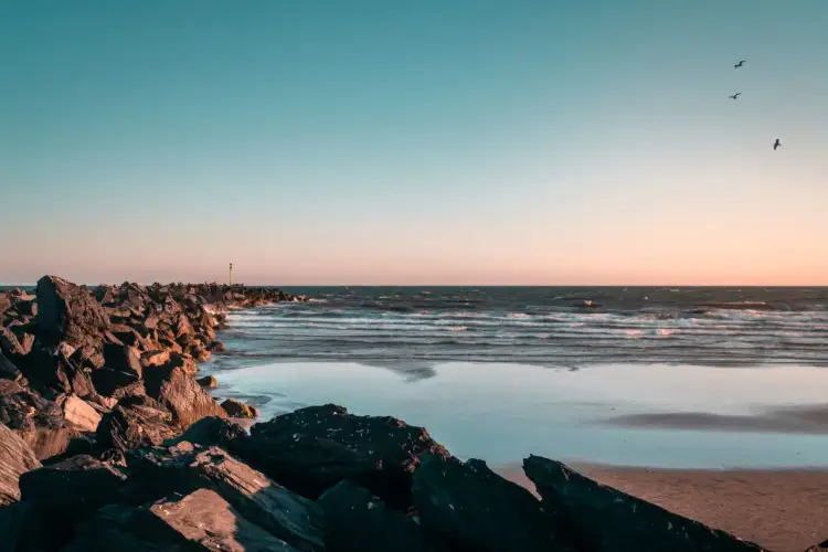 Skały na plaży o zachodzie słońca, fale na morzu. Czy Morze Czarne jest czyste? Woda wygląda na czystą, a niebo jest błękitne.