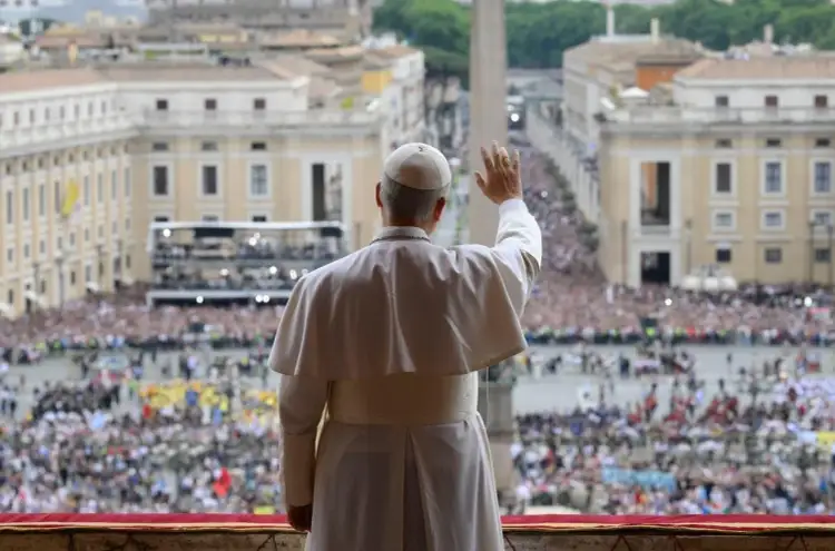 Papież w białej szacie pozdrawia tłumy zgromadzone na placu. Wznosi dłoń, jakby mówił "witaj królowo modlitwa".