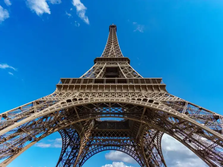Wieża Eiffla, symbol Paryża, wznosi się dumnie pod błękitnym niebem. Zastanawiasz się, ile lat ma Wieża Eiffla?
