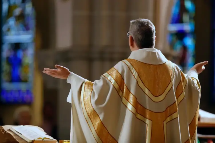 Kapłan w złotej dalmatyce, z rękami rozłożonymi, przygotowuje się do procesji z darami.