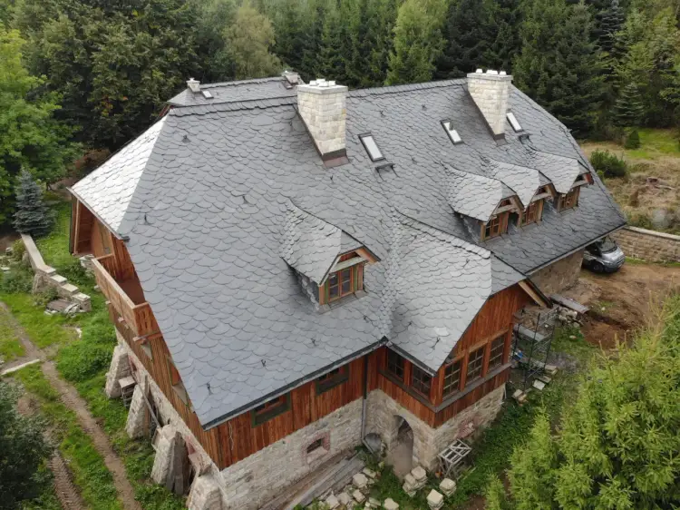 Dachówka łupek na dachu domu w lesie. Zastanawiasz się, ile kosztuje łupek na dach? To trwałe i estetyczne pokrycie.