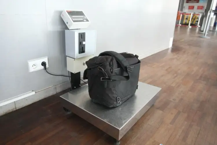 Czarna torba na wadze podłogowej, gotowa do sprawdzenia, jak zważyć walizkę w domu.