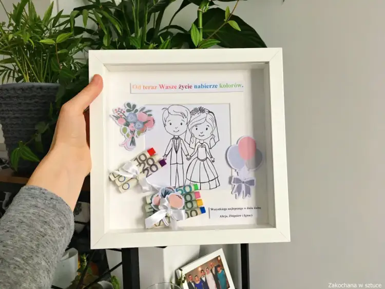 Ramka z motywem ślubnym, gdzie pieniądze są zwinięte i ozdobione wstążkami, tworząc ciekawy sposób na to, jak śmiesznie zapakować pieniądze na prezent.