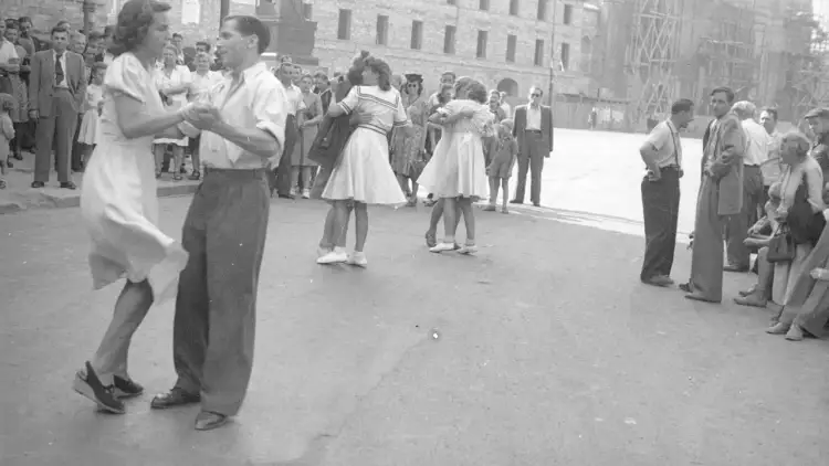 Radosne potańcówki w Warszawie. Młode pary tańczą na ulicy, otoczone przez widzów.