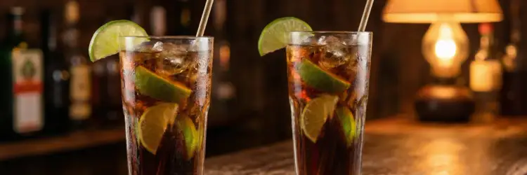 Dwa orzeźwiające rumy z colą, ozdobione kawałkami limonki, stoją na barze.