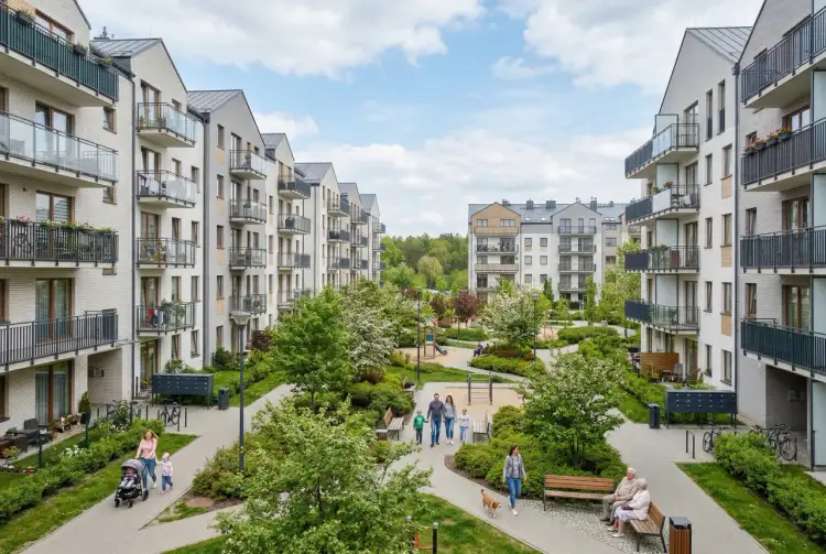 Nowoczesne osiedle z placem zabaw i zielenią, gdzie rodziny spacerują, co oznacza mieszkanie TBS – dostęp do własnego kąta w przystępnej cenie.