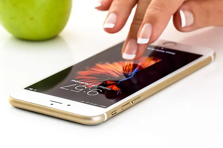 Dłoń dotyka ekranu smartfona, który przypomina nam o tym, kto wynalazł smartfon i jak zmienił świat.