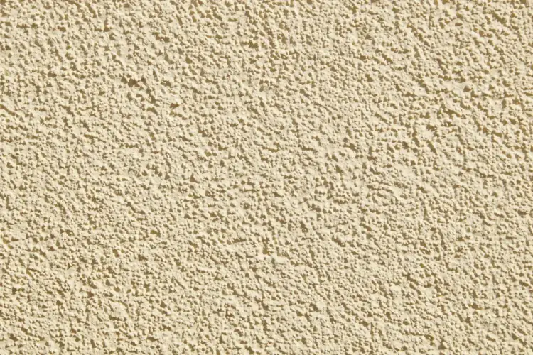 Beżowa, chropowata ściana z tynkiem strukturalnym. Dowiedz się, jak usunąć tynk strukturalny z elewacji.