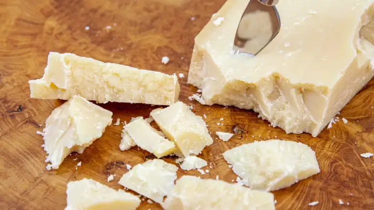 Kawałki parmezanu, znanego też jako Grana Padano, na drewnianej desce.