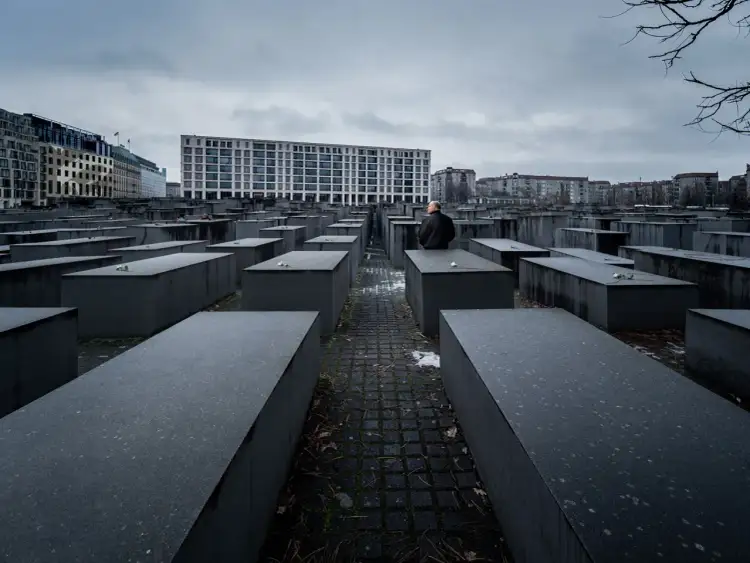 Pomnik Pomordowanych Żydów Europy w Berlinie. Betonowe bloki tworzą labirynt pamięci. Samotny mężczyzna kontempluje historię.