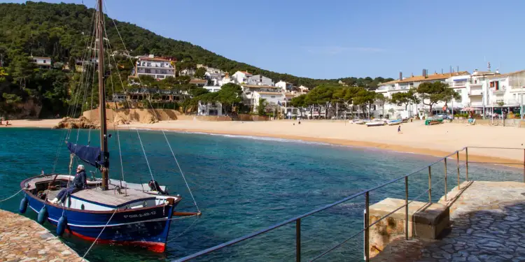 Widok na zatokę z łodzią i plażą. Potwierdza to, czy Hiszpania leży nad Morzem Śródziemnym, oferując malownicze krajobrazy.