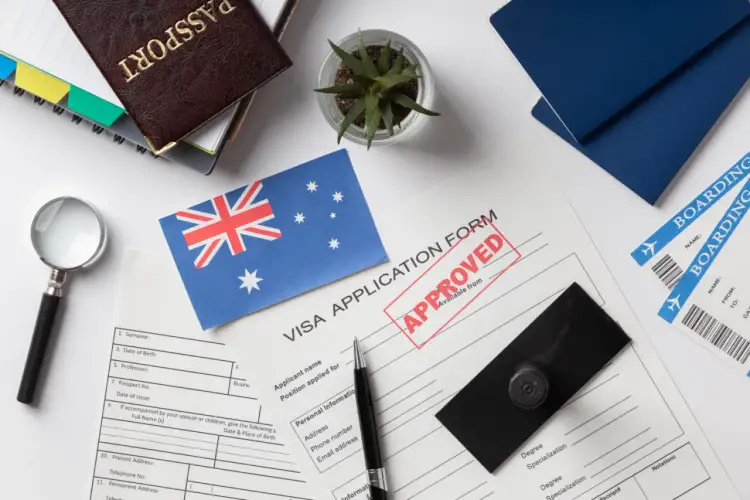 Paszport, formularz wizowy z pieczątką "APPROVED", flaga Australii, bilety lotnicze.