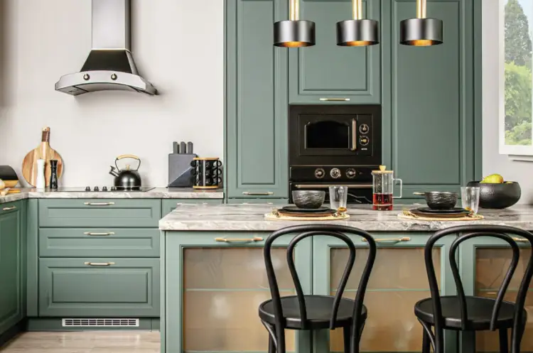 Nowoczesna kuchnia z zielonymi frontami, złotymi uchwytami i czarnymi krzesłami barowymi.