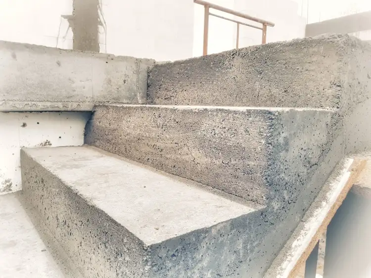 Surowe betonowe schody, gotowe do wykończenia. Widać kolejne stopnie i poręcz. To dobry moment, by zastanowić się, jak obrobic schody.