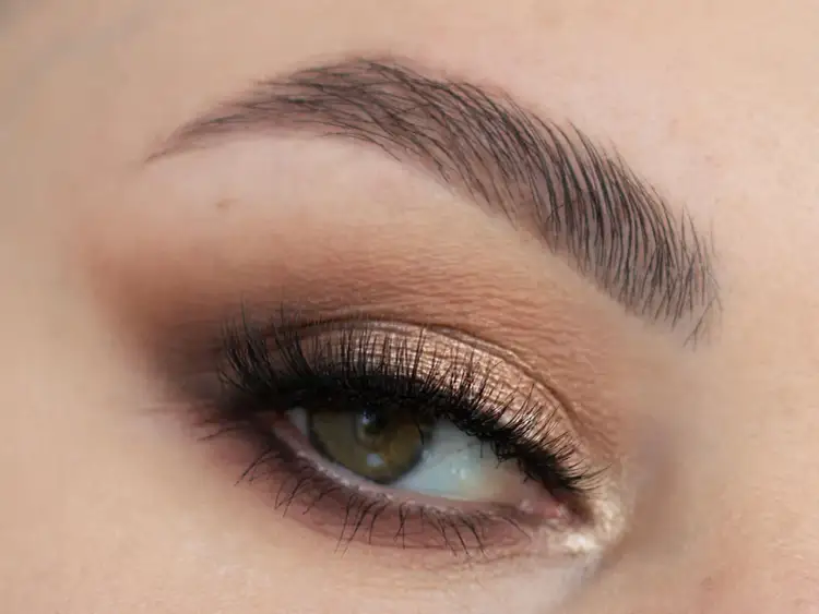 Elegancki makijaż na wesele: złociste cienie, długie rzęsy i podkreślone brwi. Idealny na specjalną okazję.