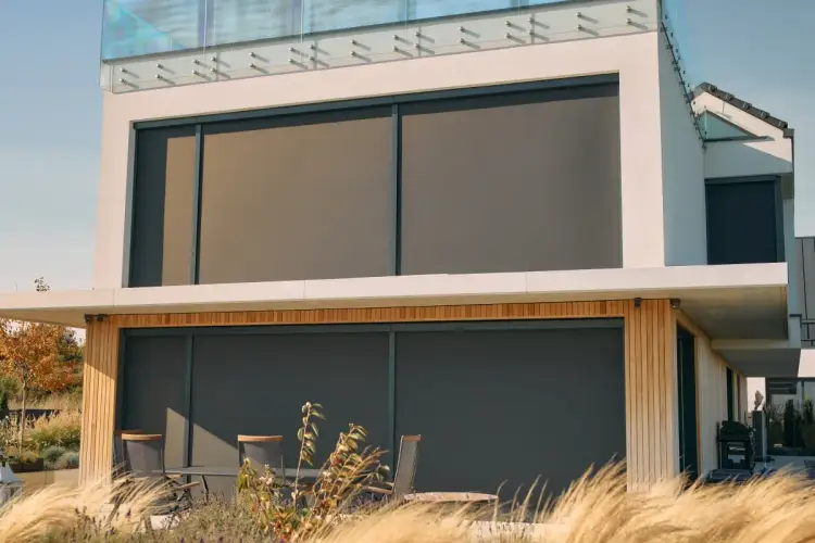 Nowoczesny dom z dużymi oknami, osłoniętymi przez eleganckie rolety fasadowe zewnętrzne.