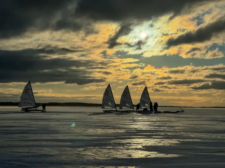 Lodowe żaglówki na zamarzniętym jeziorze o zachodzie słońca. Czy warto jechać do Dąbków na takie widoki? Tak!