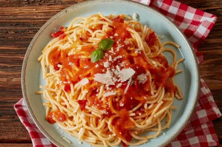 Pyszne spaghetti z sosem pomidorowym, parmezanem i listkiem bazylii. Idealne co do spaghetti na szybki obiad.