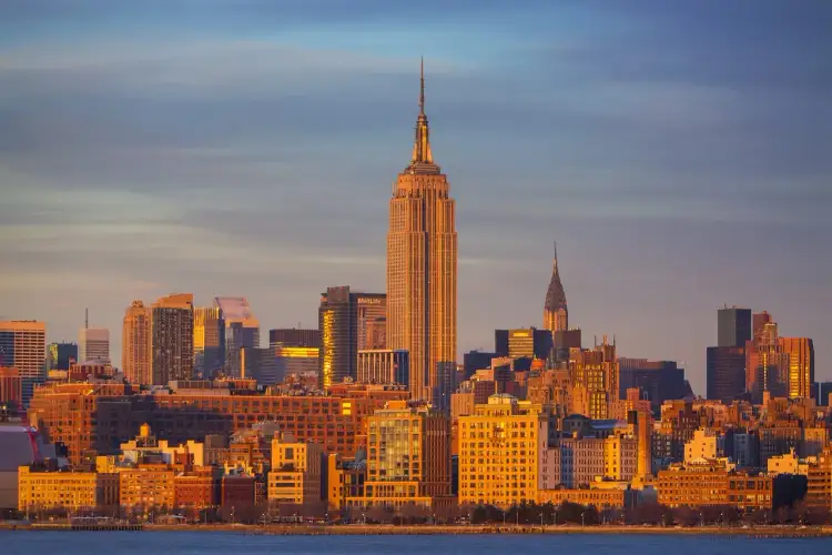 Zachód słońca nad Manhattanem. Widać Empire State Building i Chrysler Building. Zastanawiasz się, ile km do Nowego Jorku?