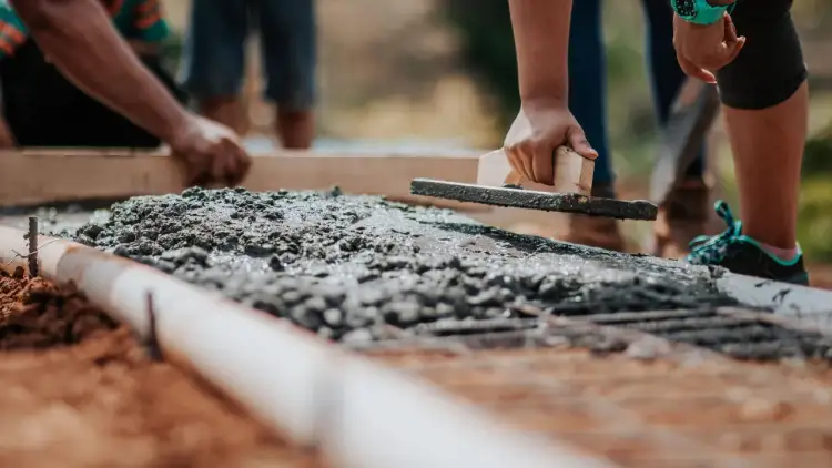 Ręczne wygładzanie świeżego betonu. Cement to tylko jeden ze składników, beton to mieszanka cementu, kruszywa i wody.