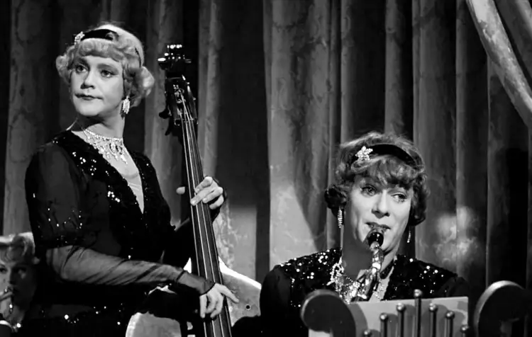 Pół żartem pół serio obsada: dwie kobiety w błyszczących sukniach grają na kontrabasie i saksofonie.