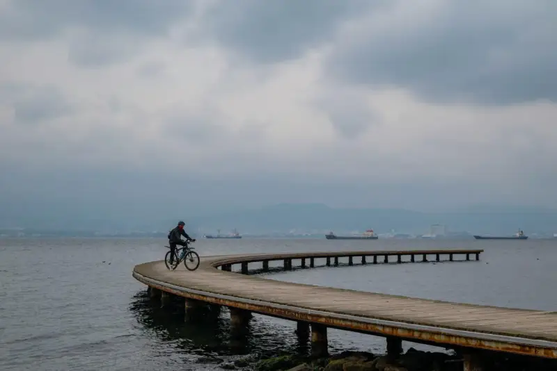 Rowerzysta przemierza malownicze trasy rowerowe nad morzem, podziwiając spokojną taflę wody i statki na horyzoncie.
