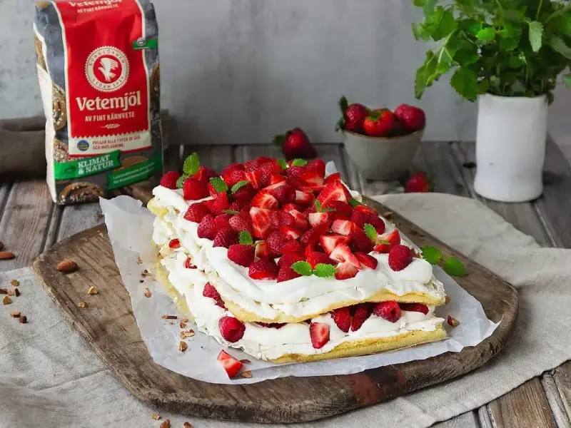 En vacker Pinocchiotårta med grädde och bär, perfekt för sommaren. Receptet kan hittas online.