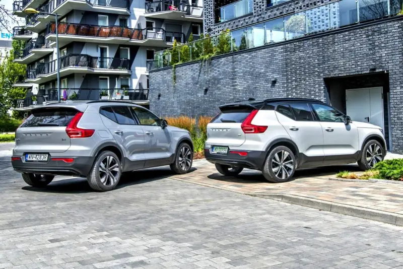 Dwa modele Volvo XC40, jeden srebrny, drugi biały, zaparkowane przed nowoczesnym budynkiem.
