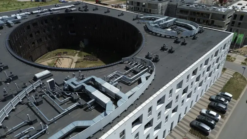 Nowoczesne budynki we Wrocławiu, z charakterystycznym okrągłym dziedzińcem i skomplikowaną instalacją wentylacyjną na dachu. Żerniki Wrocławskie w pełnej krasie.