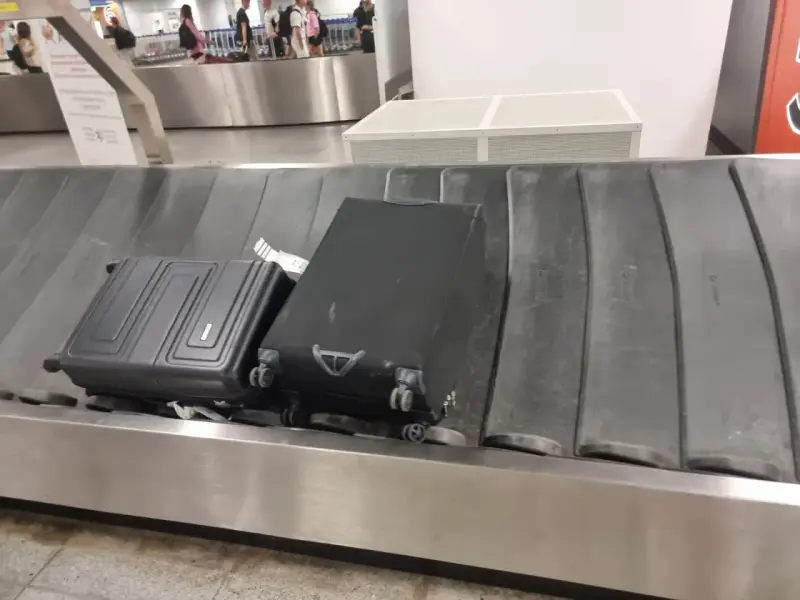 Dwa bagaże, w tym czarna walizka, czekają na odbiór na taśmie bagażowej. To typowy widok po przylocie liniami Ryanair.