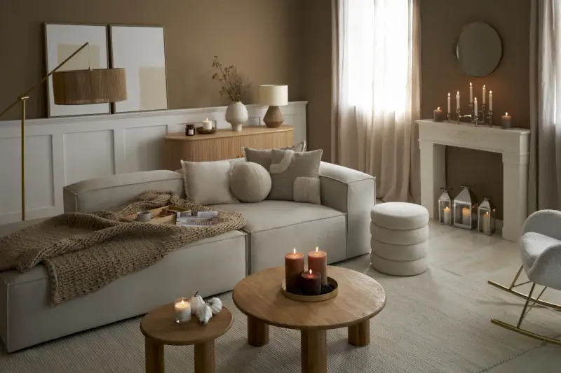 Przytulny salon w odcieniach sepia kolor. Miękki narożnik, drewniane stoliki, kominek z świecami i ciepły pled tworzą atmosferę relaksu.