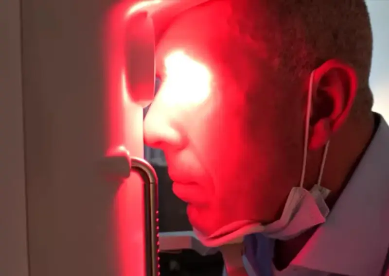 Uomo con maschera chirurgica sotto il mento, riceve fotobiomodulazione facciale. Attenzione alle fotobiomodulazione controindicazioni.